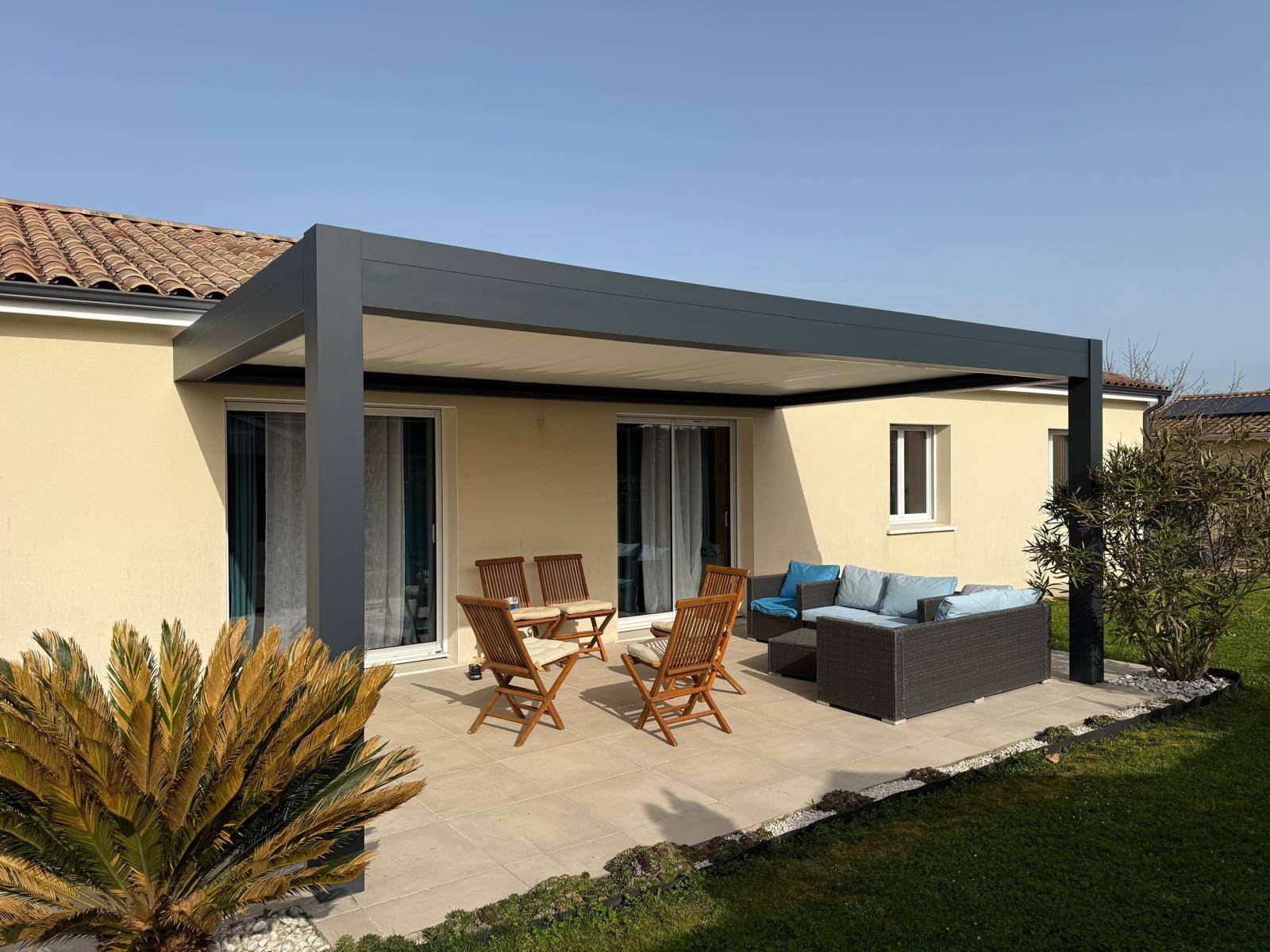 Pergola bioclimatique adossée en aluminium gris anthracite (RAL 7016) avec lames orientables blanches