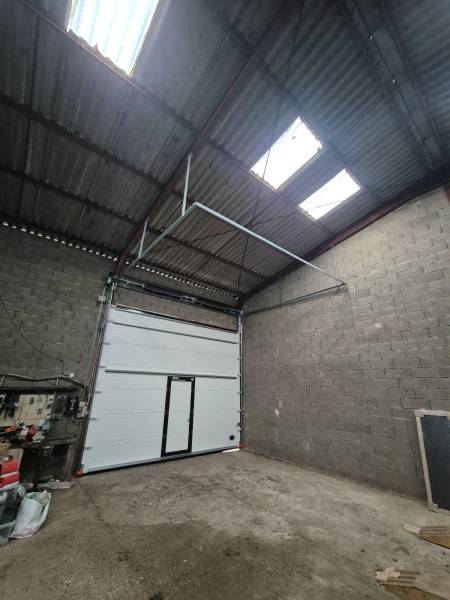 Installation d'une porte de garage sectionnelle avec panneaux sandwichs double paroi pour entrepôt industriel à Gironde sur Dropt