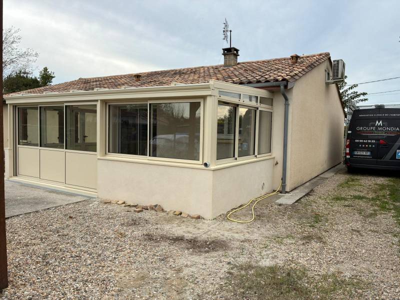 Extension de maison : Installation d'une véranda gris clair avec baies coulissantes haute performance à Lamarque.