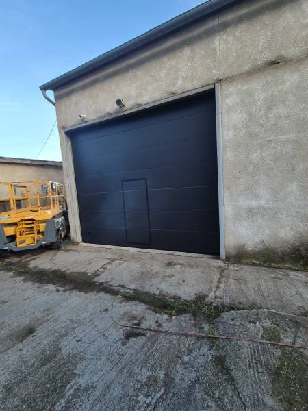 Installation d'une porte de garage sectionnelle avec panneaux sandwichs double paroi pour entrepôt industriel à Gironde sur Dropt